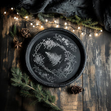 Load image into Gallery viewer, Decorative black plate with white floral design on a wooden surface with pine branches and lights.