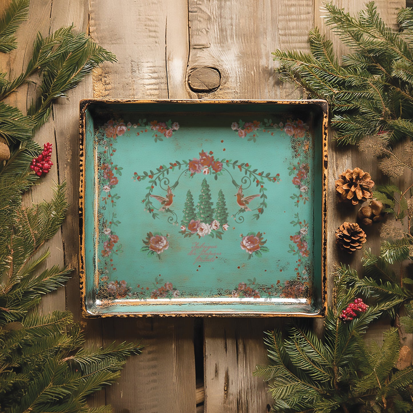 Decorative tray with floral design on a wooden background with greenery
