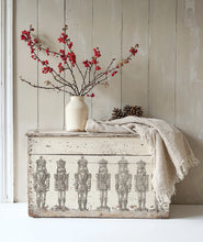 Load image into Gallery viewer, Decorative chest with nutcracker design using Iron Orchid Design Stamps, white vase with red branches, and beige blanket against a wooden wall.