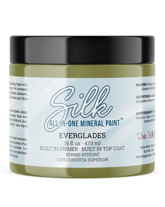 A jar of Silk All-In-One Mineral Paint in Everglades, featuring a light olive green body, a black lid, and a white label with blue and red text, set against a plain white background.