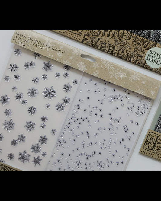 Iron Orchid Designs clear stamp set featuring decorative stamp blocks with silver snowflakes and rhinestones, shown alongside matching printed masks and a bonus mask insert.