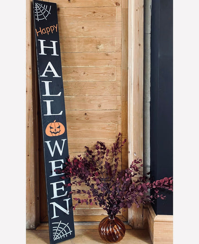 Halloween-themed wooden sign with decorative elements against a wooden wall.