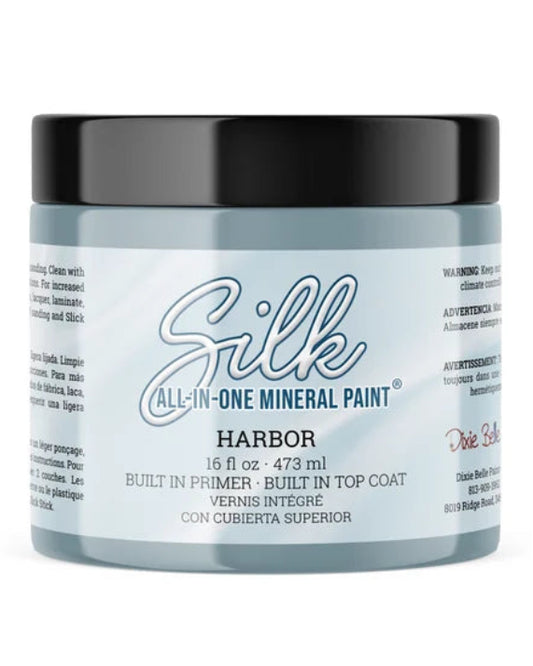 A jar of Silk All-In-One Mineral Paint in the color Harbor, featuring a light blue-gray jar, a black lid, and a white label with blue and black text.