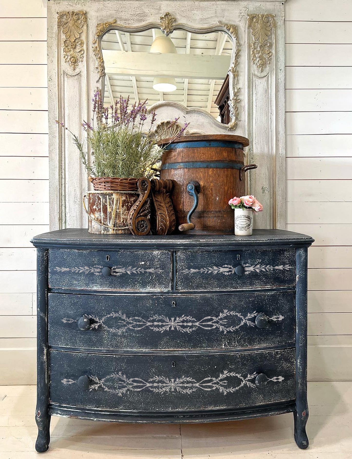 Vintage dresser with decorative elements using IOD Paint Inlay against a wooden wall.