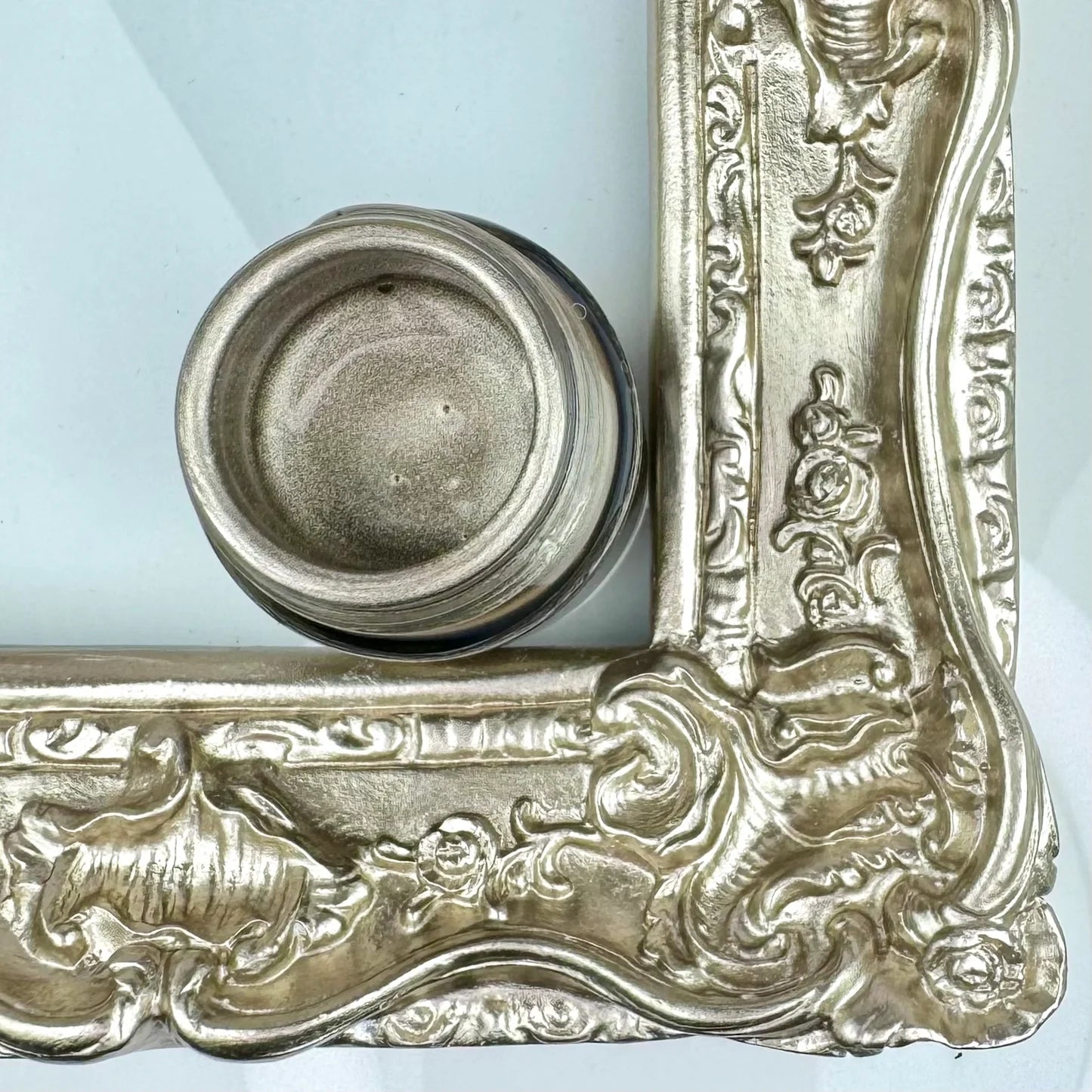 Decorative silver frame with intricate designs on a light blue background