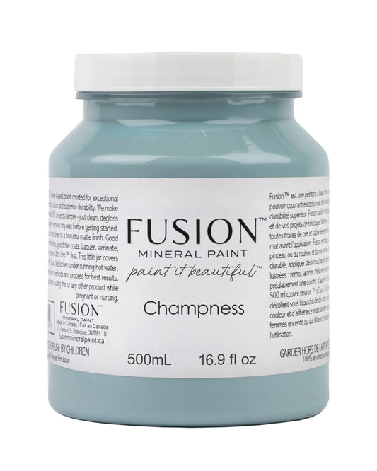 A 500 mL jar of Fusion Mineral Paint in the shade 'Champness', featuring a light blue-gray paint color and a white lid, shown on a plain white background.